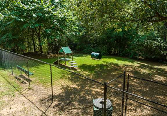 The pet bark park with trees and obstacles and a bench at Summerchase at Riverchase in Hoover, Alabama.