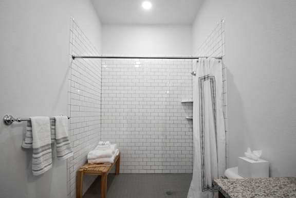 a white bathroom with a shower and a table with towels at 20 Midtown, Alabama, 35233