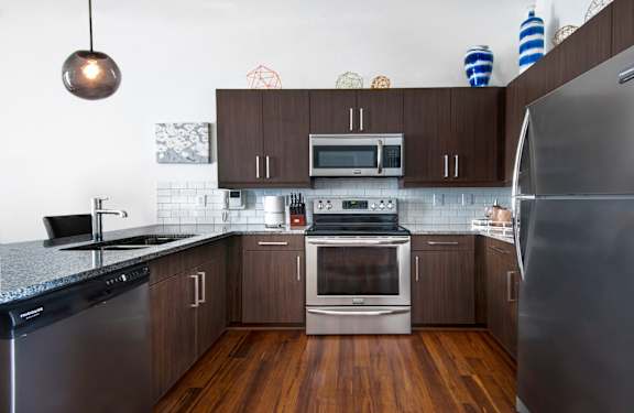 a kitchen with stainless steel appliances and dark wood cabinets at 20 Midtown, Birmingham, AL, 35233