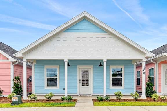 a blue house with a white porch and pink and blue houses