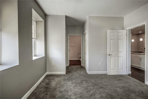 an empty living room with a white door and a closet
