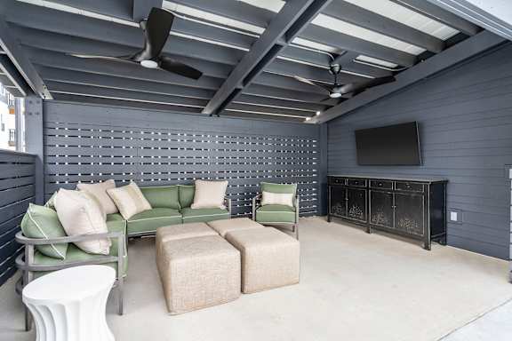 A living room with a green couch, a white table, and a television.