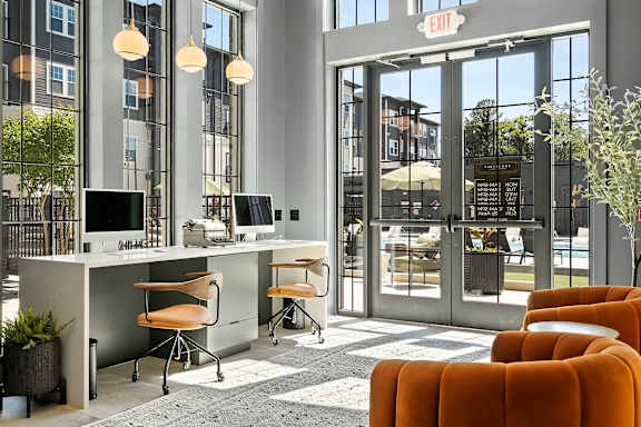 A modern office space with orange chairs and a glass door entrance.