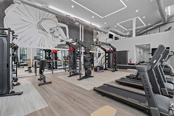 A gym with a variety of equipment including treadmills, weights, and exercise machines.