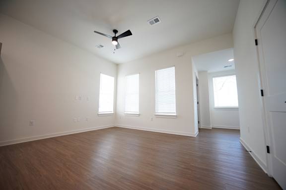 A living room with a ceiling fan and wooden floors at Wesley Place Apartments in Birmingham, AL