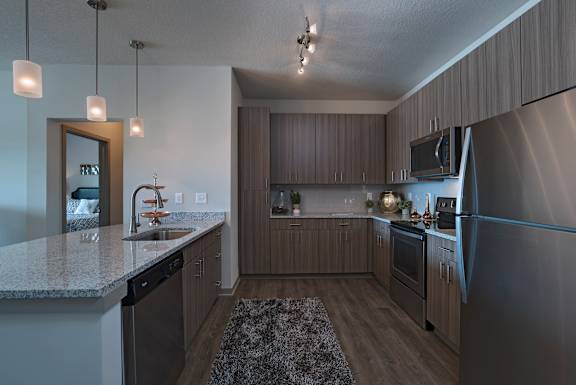 A modern kitchen with a granite countertop and stainless steel appliances.