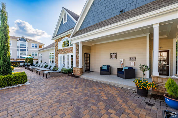 A brick patio leads to a white building with a black roof.