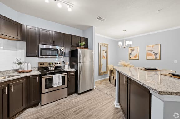 A modern kitchen with dark brown cabinets and stainless steel appliances.