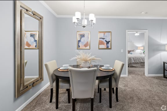 A dining room with a table set for two and a mirror on the wall.