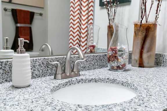 A bathroom sink with a white counter top and a silver faucet.