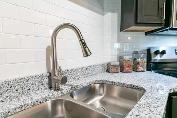 A modern kitchen with a granite countertop and a stainless steel sink.