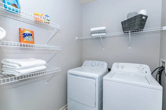 A laundry room with a washer and dryer and a basket of towels.