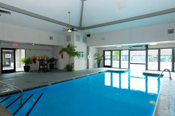 A large indoor swimming pool with a table and chairs in the background.