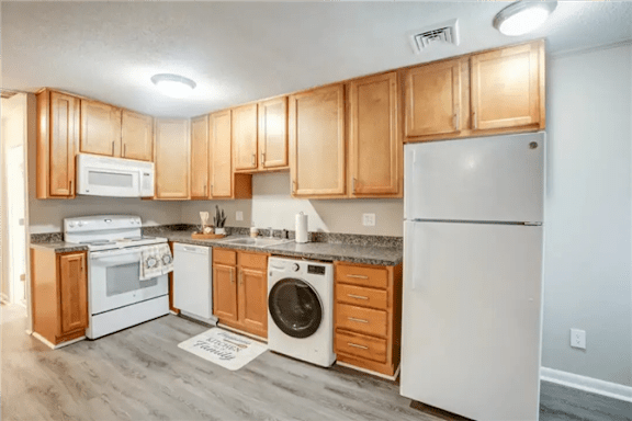 A kitchen with wooden cabinets and white appliances.