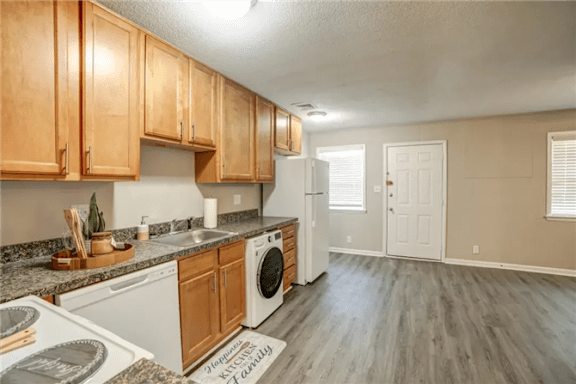 A kitchen with wooden cabinets and a white dishwasher.