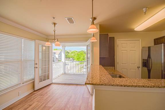 a kitchen with a counter and a door to a balcony at 10X Audubon Park apartments in Daphne, AL
