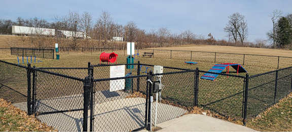 a dog park with a chain link fence and playground equipment