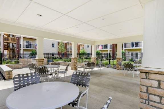 A patio with tables and chairs is surrounded by a brick wall.