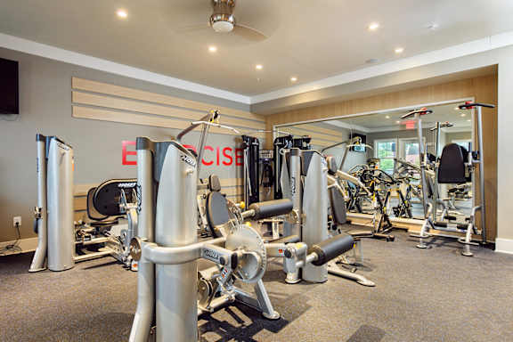 A gym with a variety of equipment including treadmills, weights, and exercise machines.