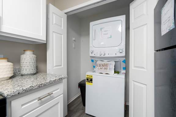 A kitchen with granite countertops, white cabinets, and a washer and dryer unit at Summerchase at Riverchase in Hoover, Alabama.