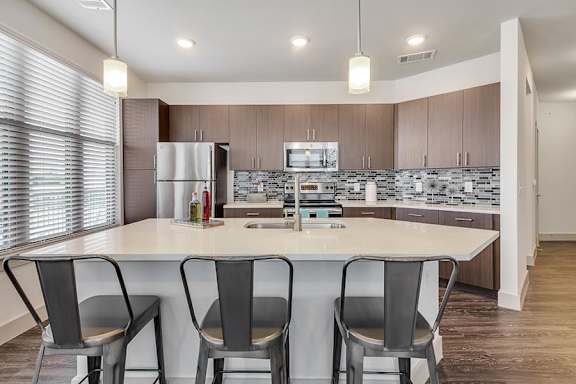 Modern kitchen with island seating and pendant lighting at The Mark at Midtown Apartments, Dallas