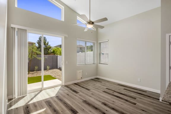an empty room with a ceiling fan and a sliding glass door to a backyard
