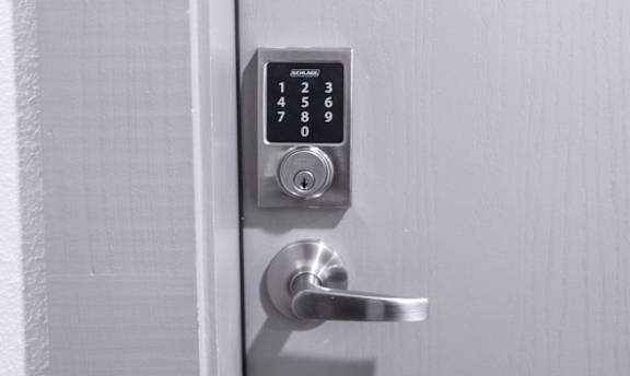 A smart lock keypad on a door handle with numbers 0-9 displayed.