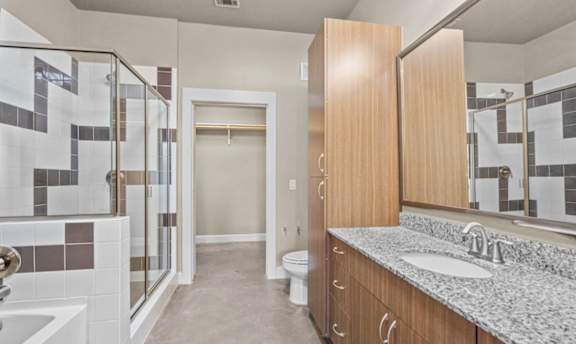 Bathroom with walk in shower and granite vanity at Matilda at Lower Greenville Apartments, Texas