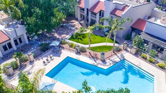 Aerial view of pool area with palm trees and lawn at Gentrys Walk Apartments, Mesa, AZ 85204