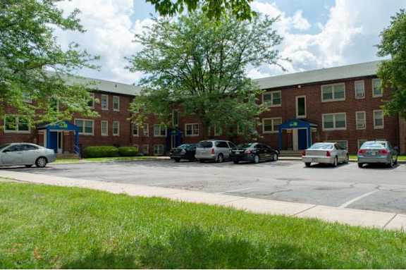 A parking lot in front of a red brick building with cars parked.