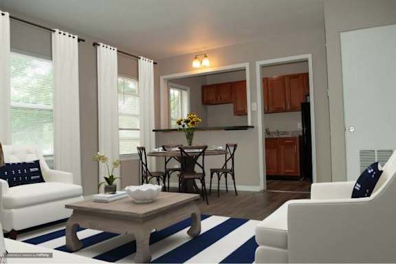 A living room with a white couch, a coffee table, and a dining table with chairs.