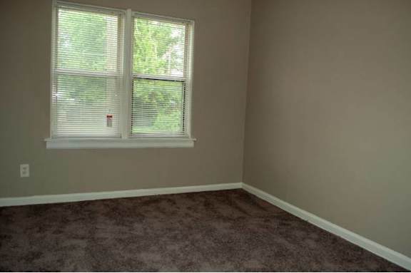 A room with a window and carpeted floor.