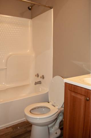A white toilet in a bathroom with a wooden cabinet.