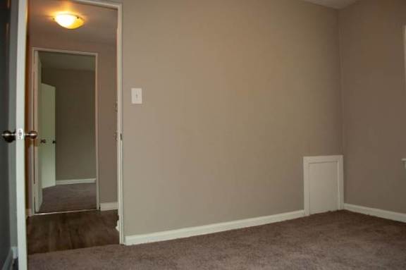 A room with a carpeted floor and a doorway leading to another room.