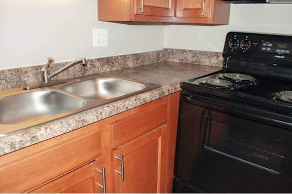 A black stove is in a kitchen with wooden cabinets.