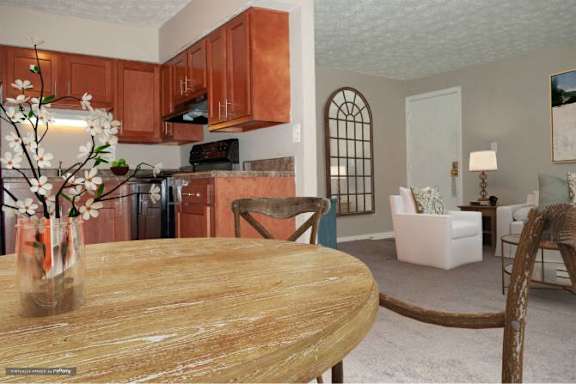 A kitchen with brown cabinets and a wooden table with a vase of flowers on it.