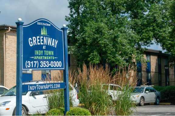 A sign for Greenway at Indy Town Apartments with a phone number and website listed.