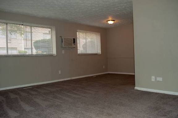 A room with a carpeted floor and a window with blinds.