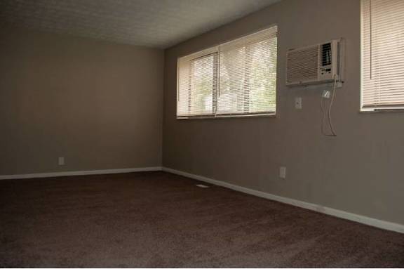 A room with a window and an air conditioner on the wall.