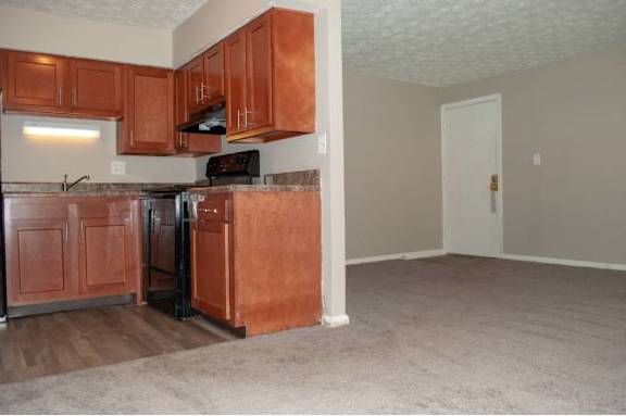 A kitchen with brown cabinets and a black refrigerator.