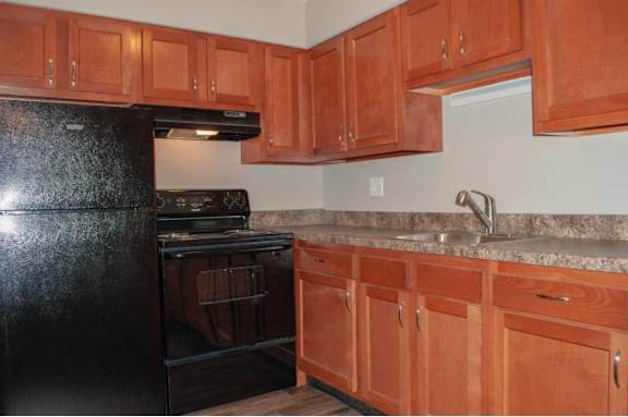 A kitchen with wooden cabinets and a black refrigerator.