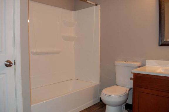 A white toilet sits next to a white bathtub in a bathroom.