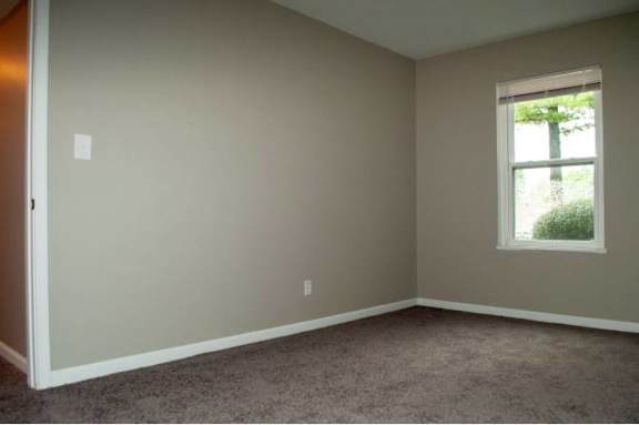 A room with a window and carpeted floor.