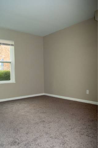 A room with a window and carpeted floor.