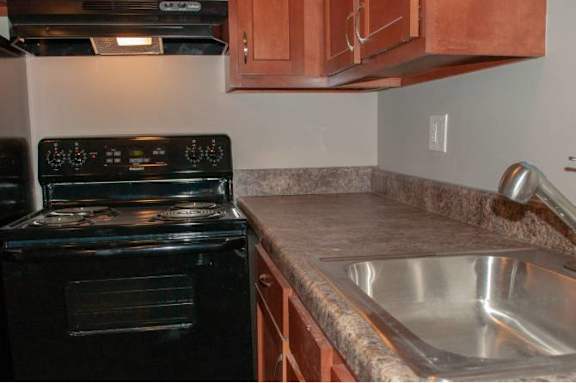 A black oven sits next to a stainless steel sink in a kitchen.
