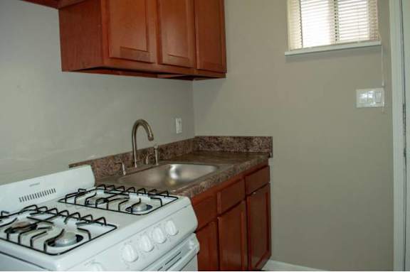 A white gas stove is in a kitchen with brown cabinets.