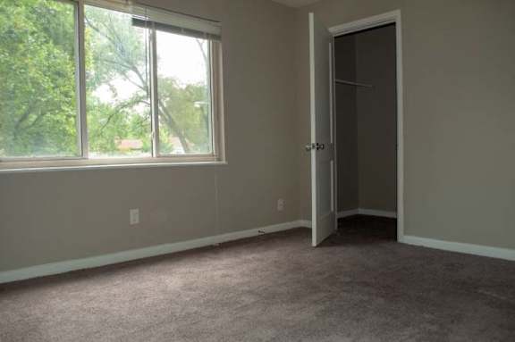 A room with a carpeted floor, a door, and a window.
