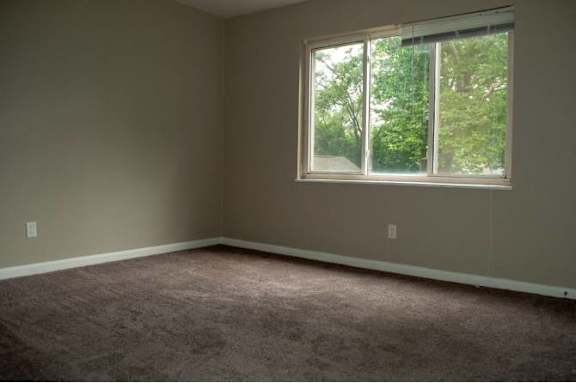 A room with a carpeted floor and a window.
