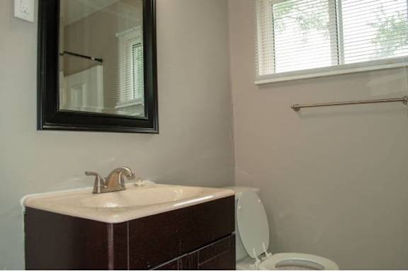 A bathroom with a sink, toilet and mirror.