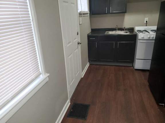 A kitchen with a white stove and black countertops.